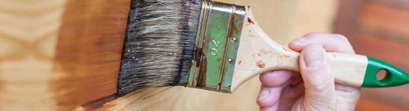 Close up of a person using a brush to apply varnish on wood