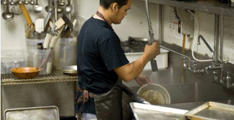 a dishwasher at a restaurant cleans pots and pans